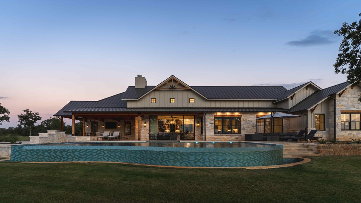 Backyard view of a house with an illuminated pool and patio at dusk in central Texas | J Bryant Boyd