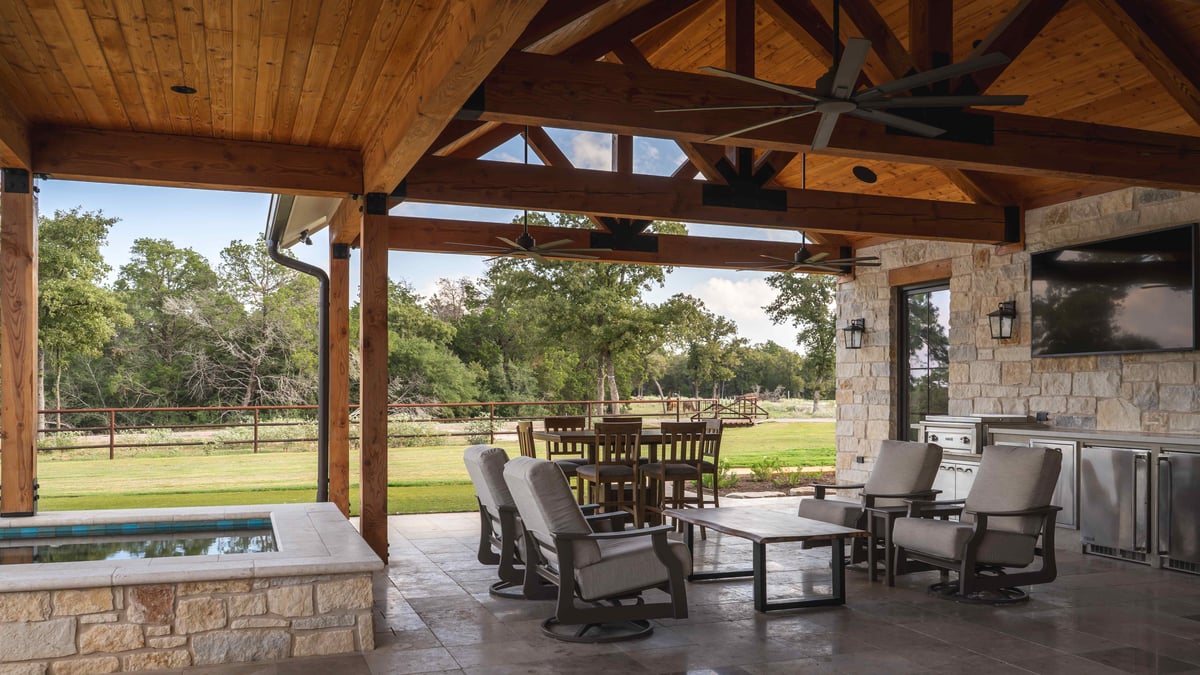 Covered patio with a seating area, dining table, and outdoor kitchen in central Texas | J Bryant Boyd