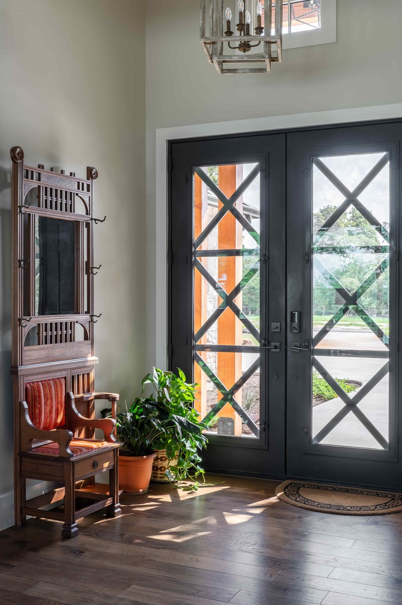 Entryway with glass-paneled double doors, a wooden bench, and indoor plants in central Texas J Bryant Boyd