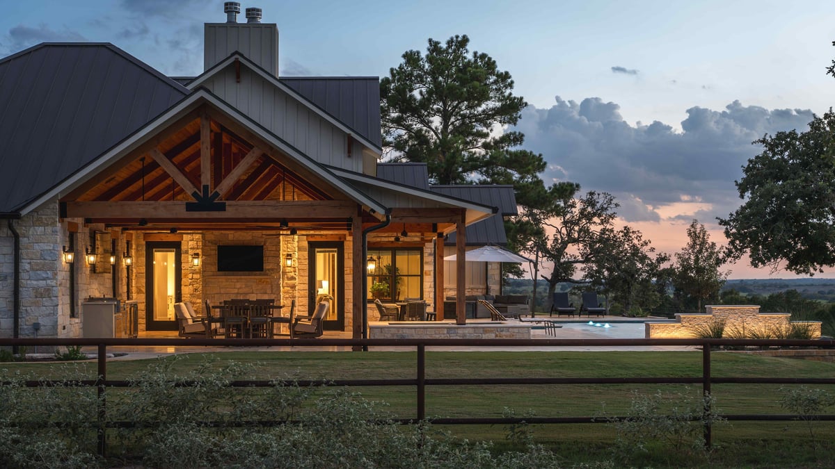 House exterior with a lit patio, seating area, and pool at dusk in central Texas | J Bryant Boyd