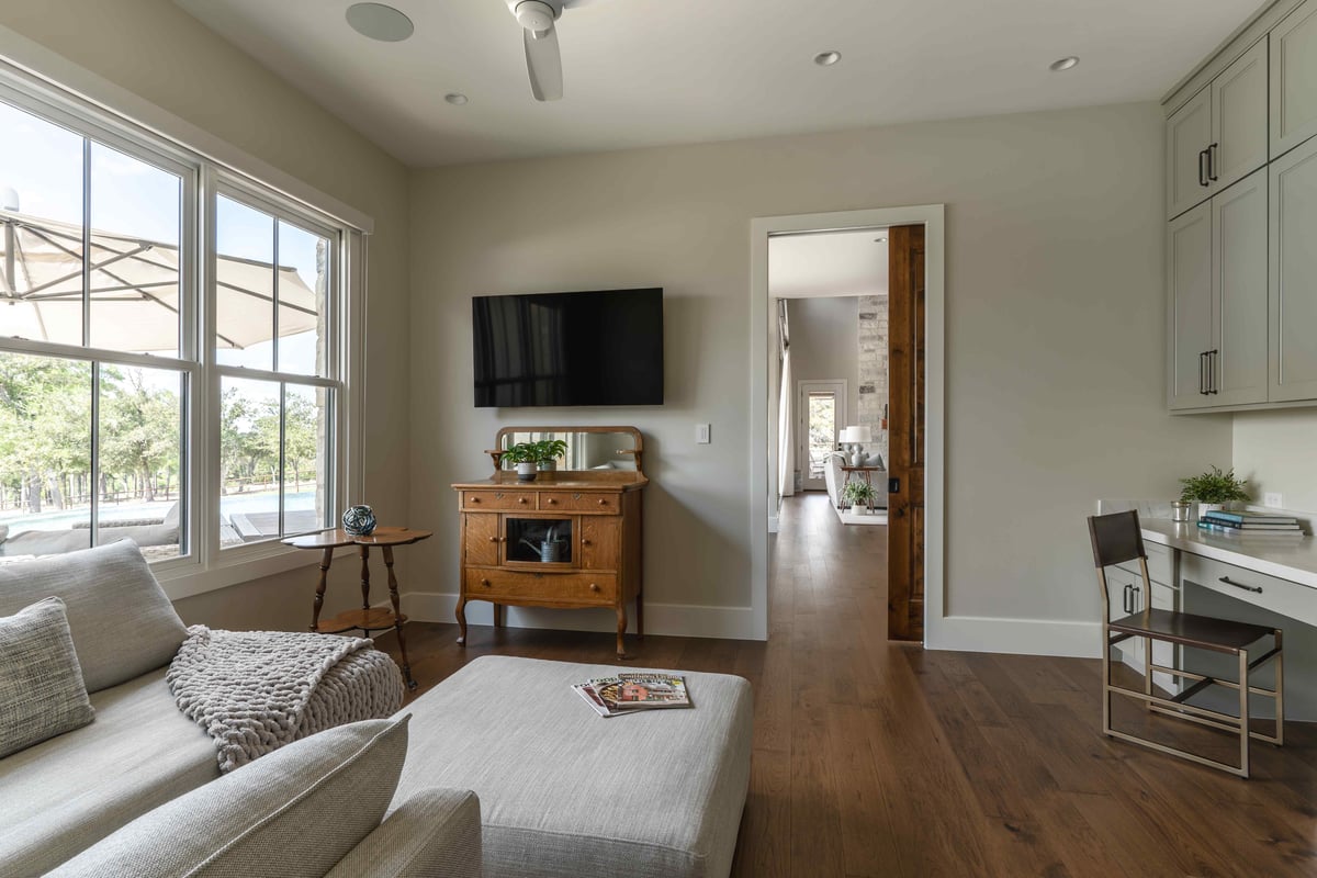 Living area with a TV, wooden cabinet, and large window overlooking the outdoors | J Bryant Boyd