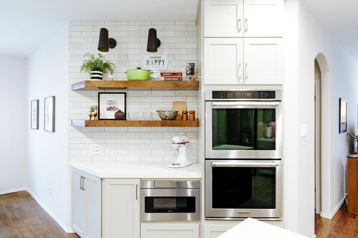 Modern kitchen remodel with white cabinets, double ovens, and wooden shelves in Georgetown, TX by J Bryant Boyd