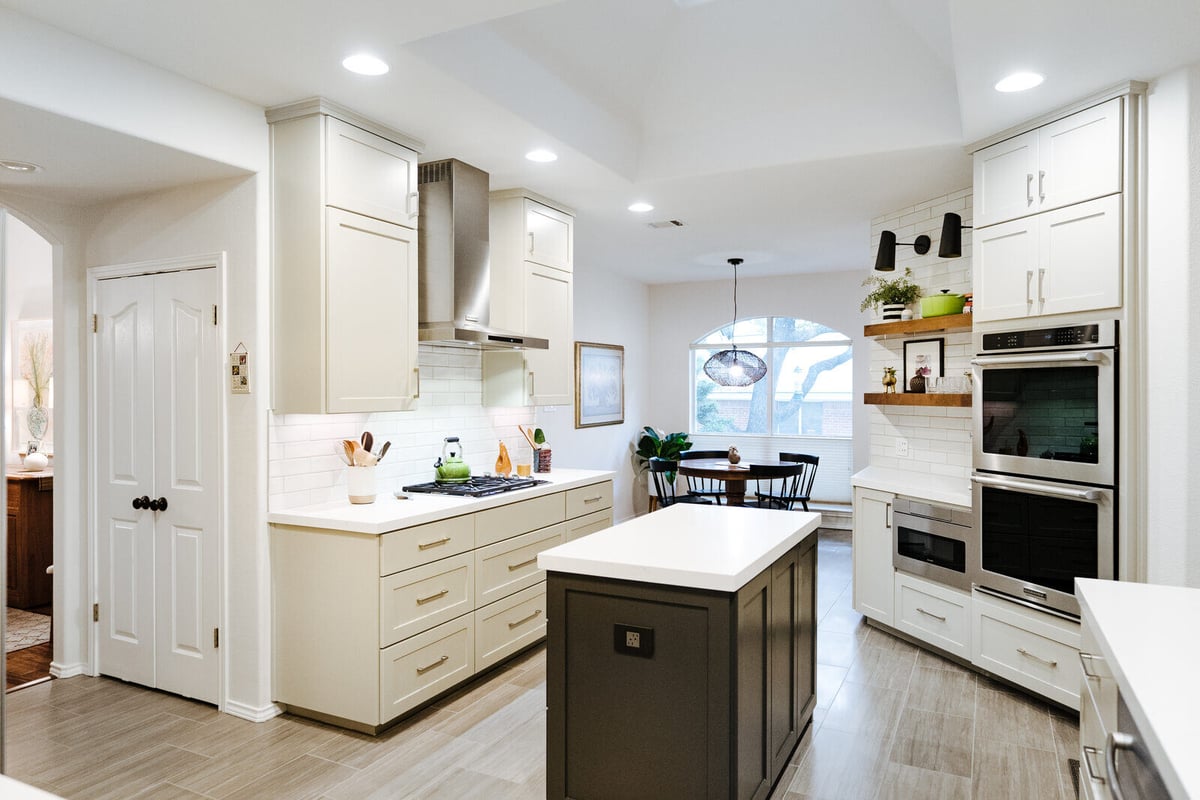 Wide-angle view of a remodeled kitchen with island and stainless steel range in Georgetown, TX by J Bryant Boyd