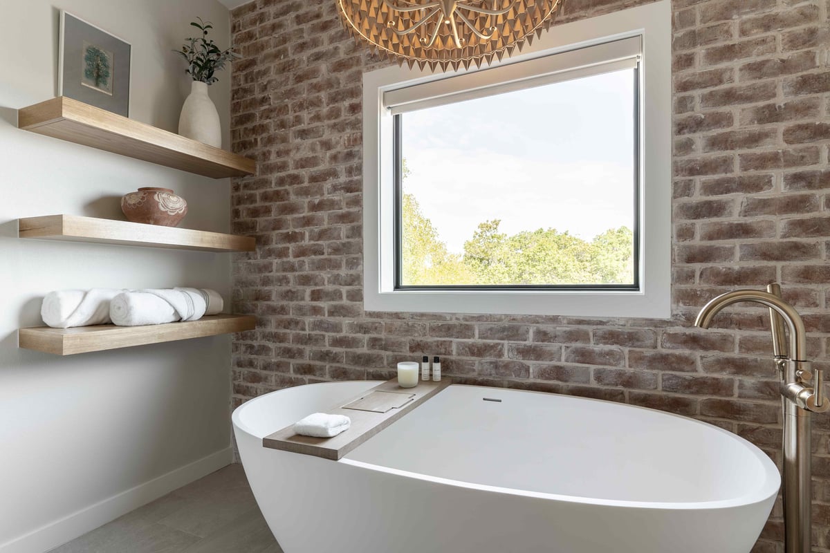 Freestanding tub with brick backsplash wall and floating shelves | J Bryant Boyd