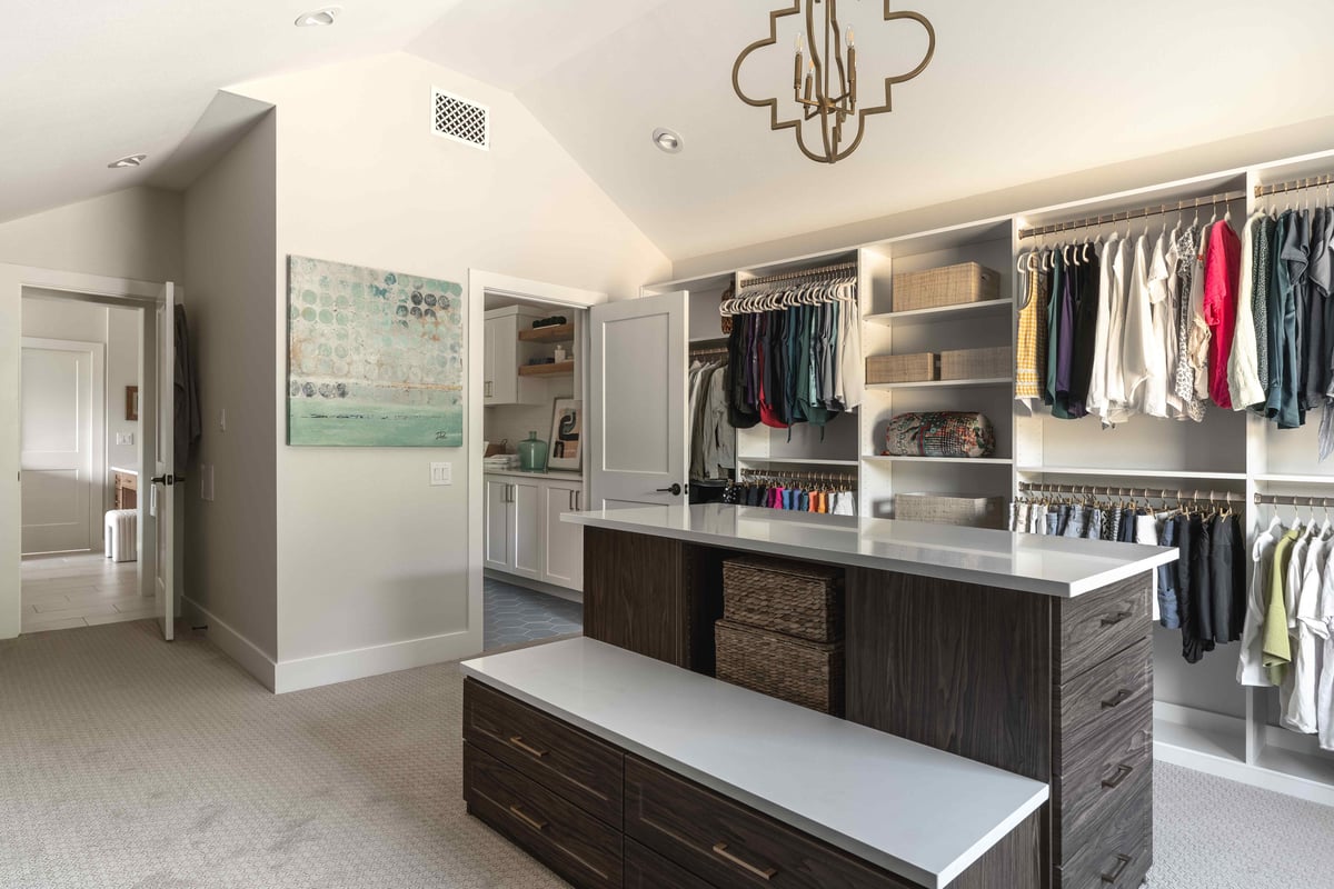 Large walk in closet with chandelier and entry to bathroom | J Bryant Boyd