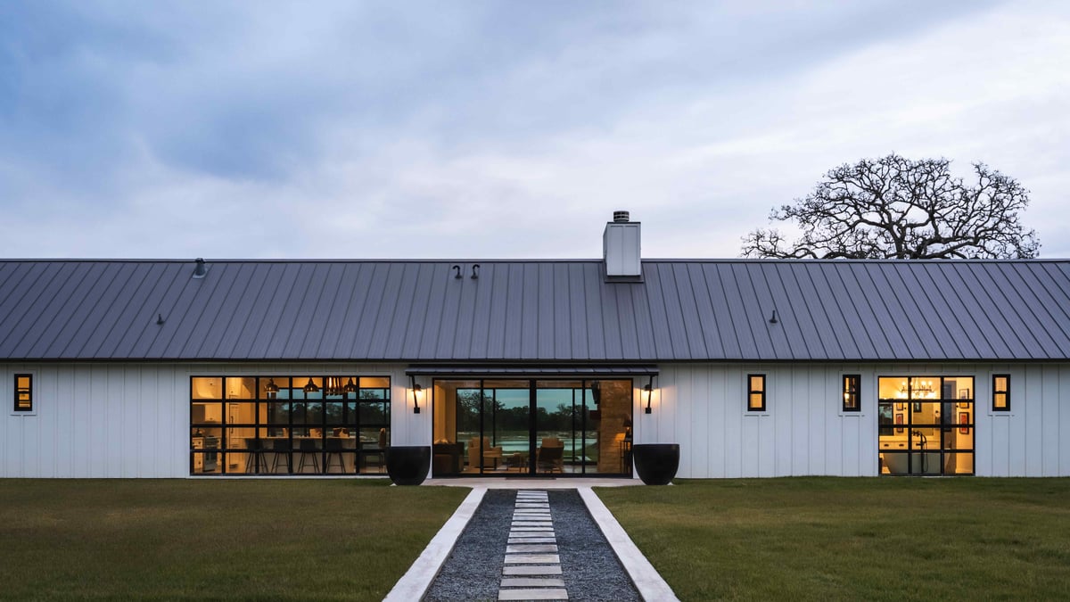 Front view of a modern farmhouse with a metal roof and a symmetrical walkway | J Bryant Boyd