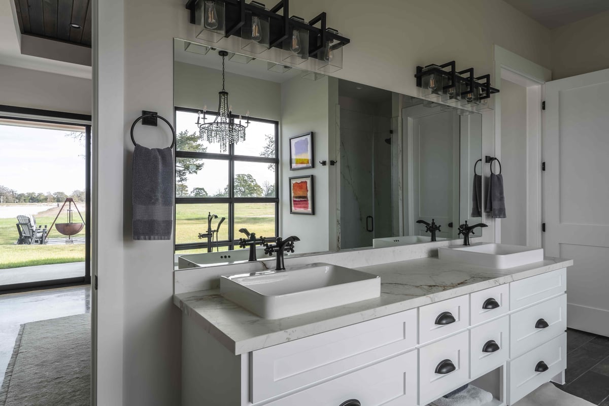 Modern bathroom with dual sinks, featuring a chandelier and abstract art | J Bryant Boyd