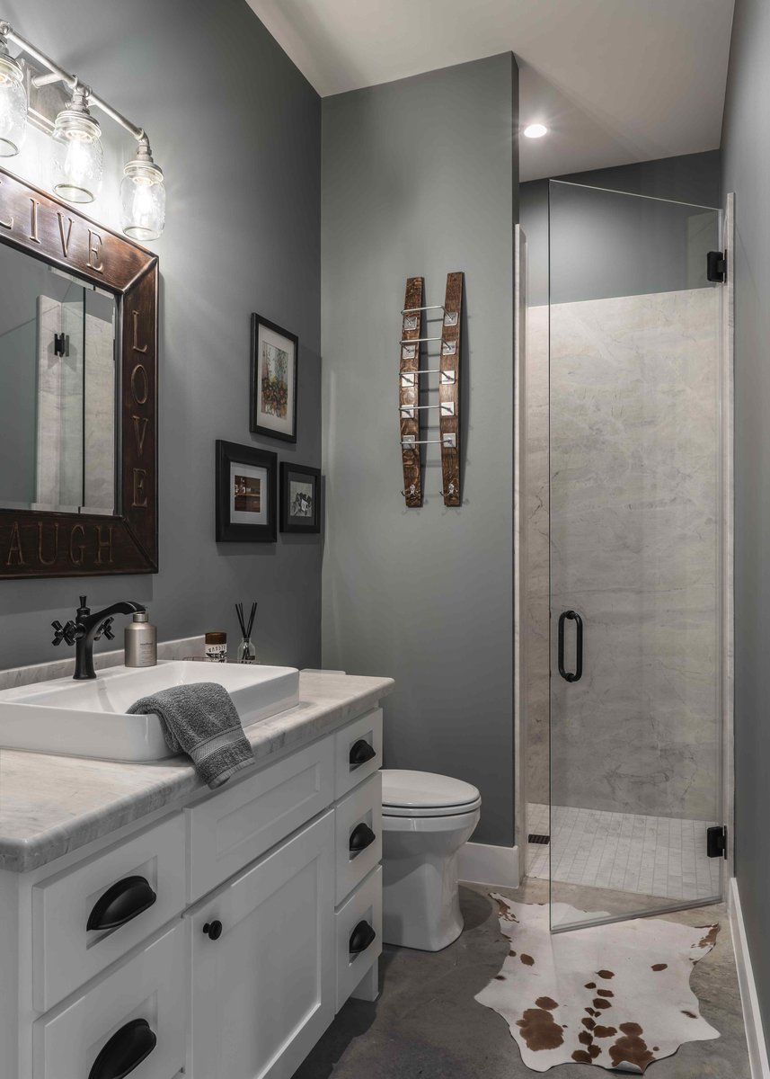 Stylish bathroom with gray walls, a white sink, and a glass-enclosed shower, decorated with rustic and modern accents | J Bryant Boyd