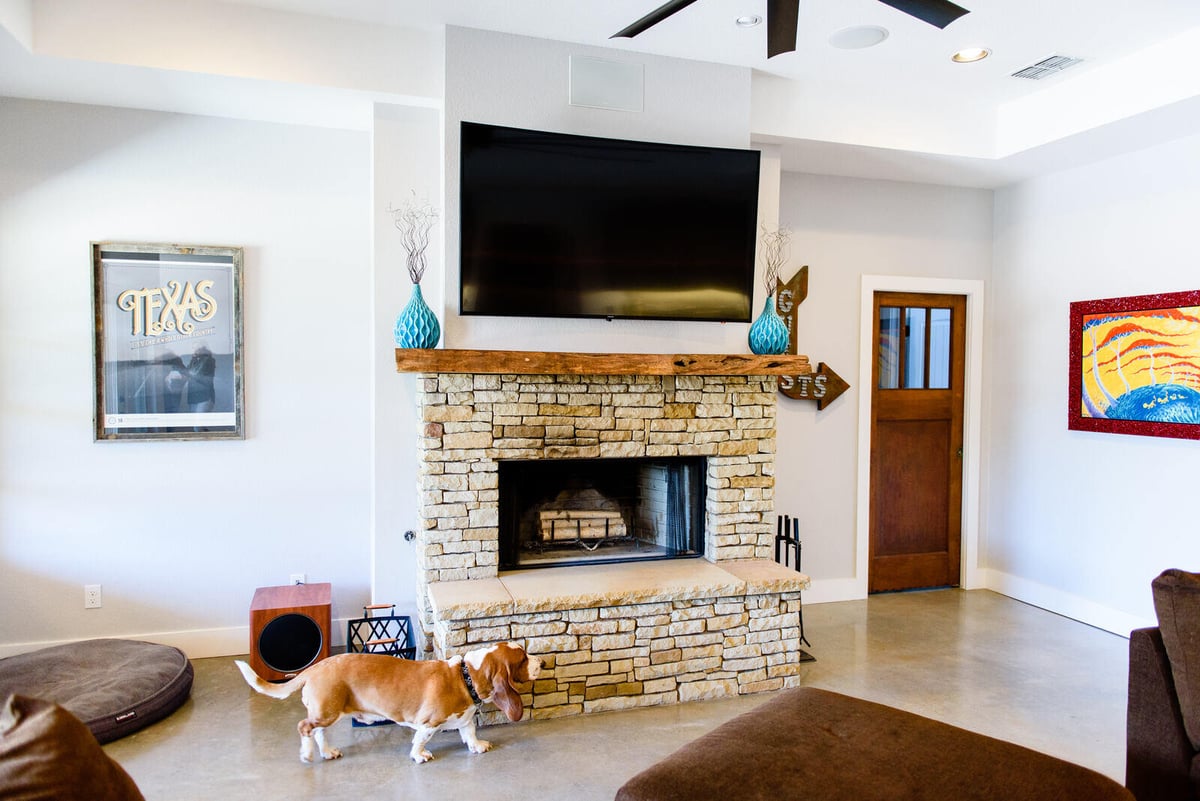 Cozy living room with stone fireplace and mounted TV in a Georgetown, TX custom home by J Bryant Boyd