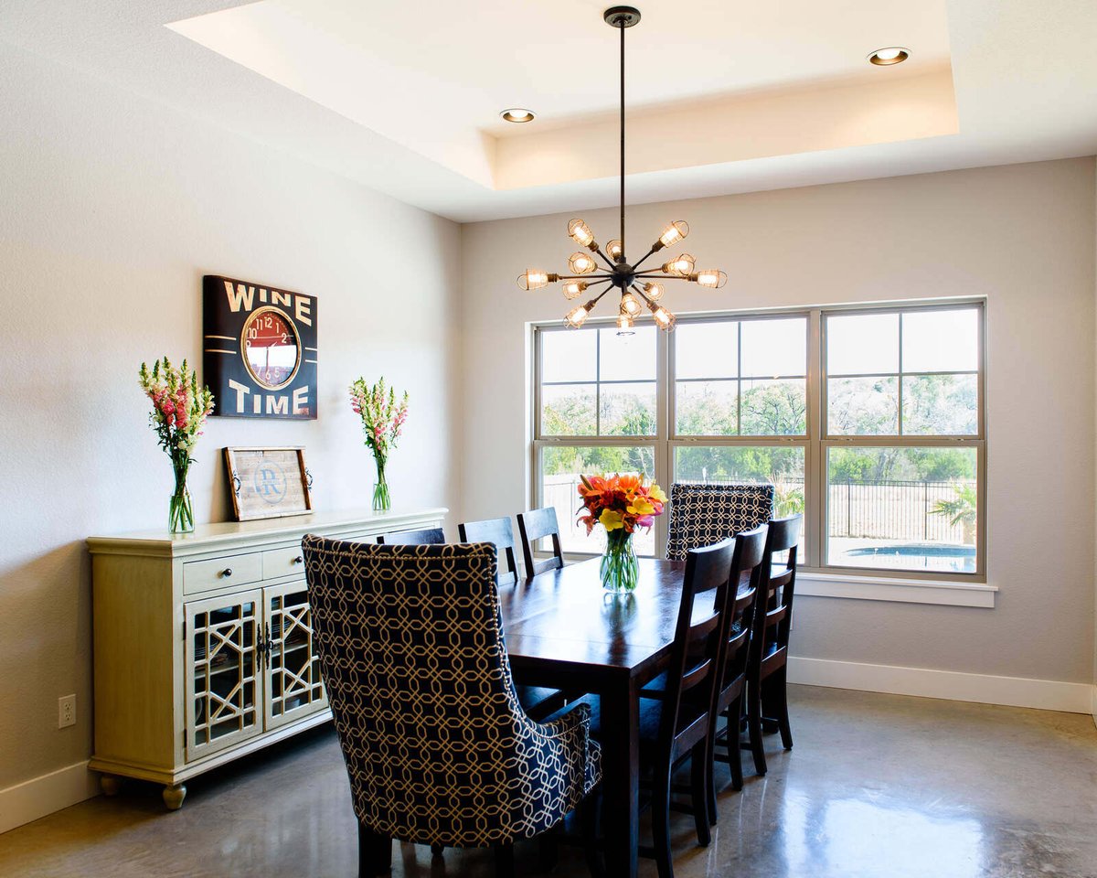 Dining room with modern chandelier and large windows, designed by J. Bryant Boyd in Georgetown, TX