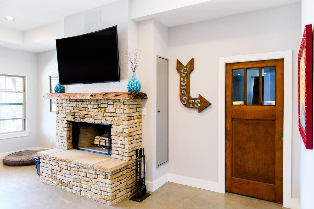 Living room with stone fireplace and large TV, part of a remodel by J. Bryant Boyd in Georgetown, TX