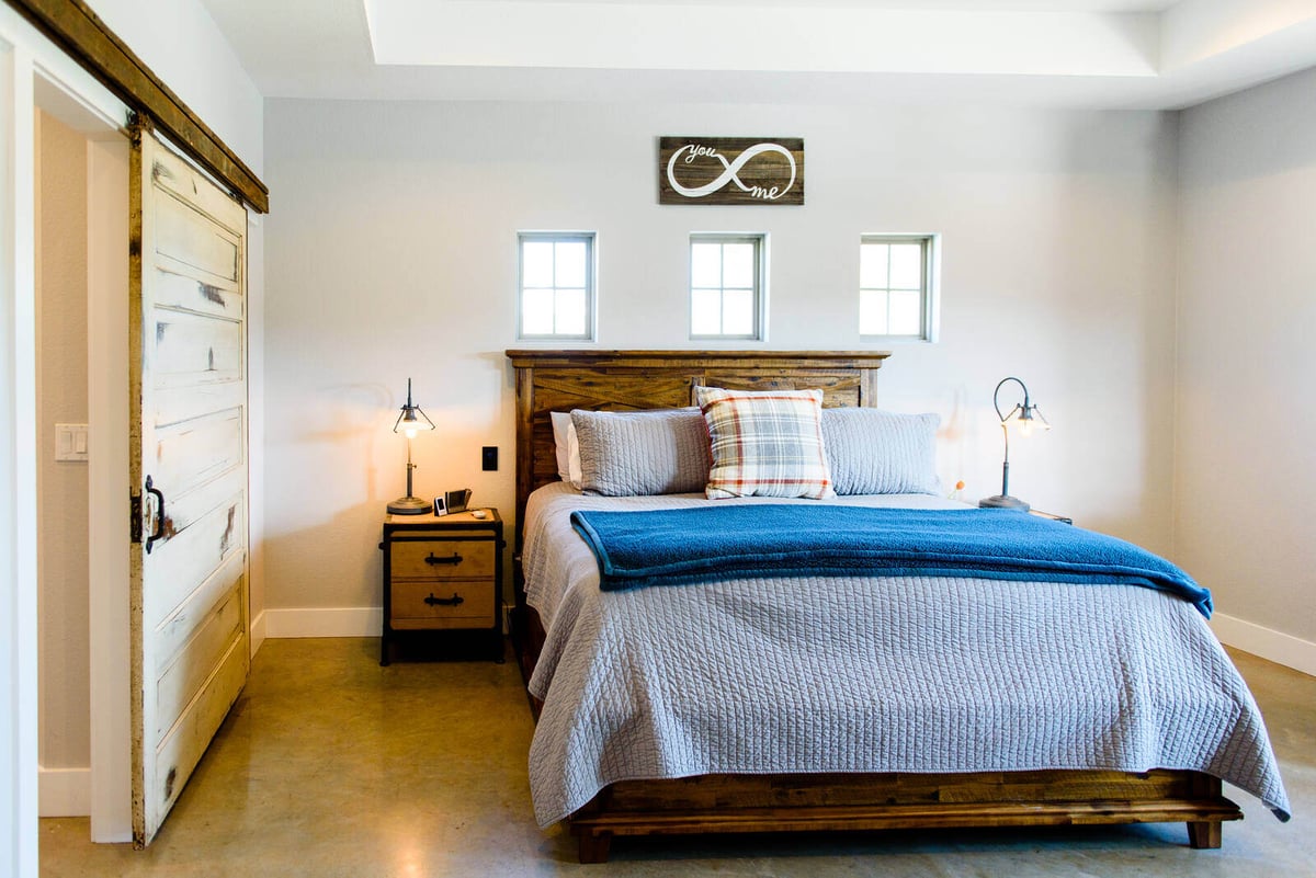 Master bedroom with vintage sliding door and custom wood bed frame in Georgetown, TX by J Bryant Boyd Design-Build