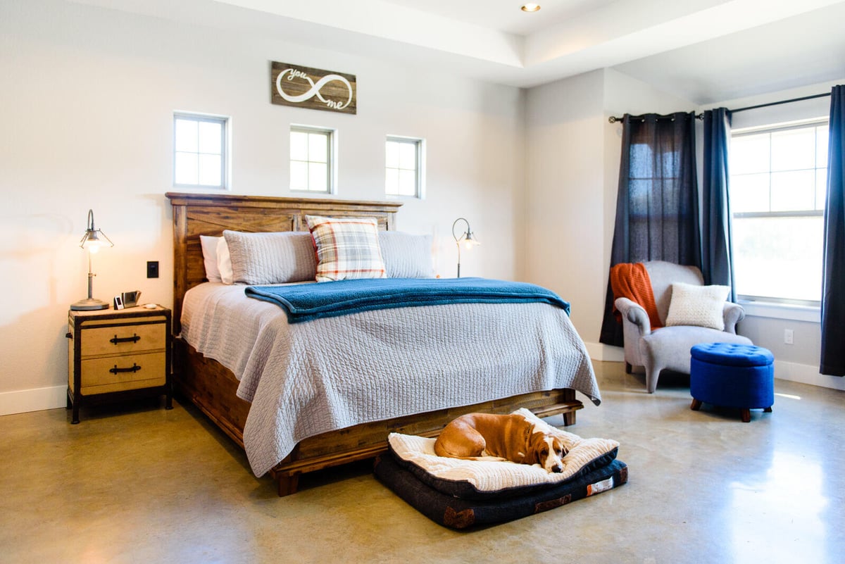 Master bedroom with wooden bed frame and dog resting by the bed in a Georgetown, TX home by J Bryant Boyd