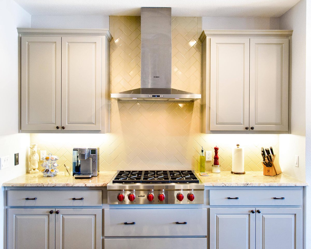 Modern kitchen with beige cabinetry and stainless steel range in a Georgetown, TX home by J Bryant Boyd Design-Build