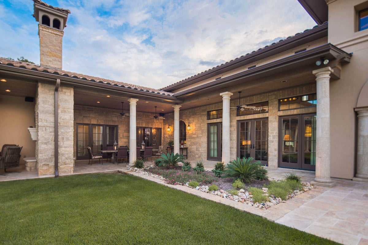 Charming outdoor patio with warm lighting and wooden table in a custom home by J Bryant Boyd in Georgetown, TX