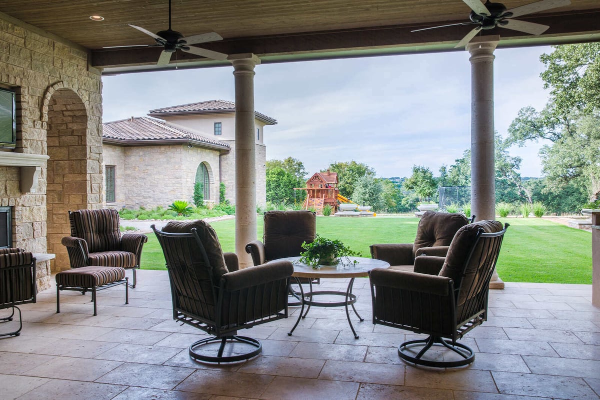 Covered outdoor seating area with ceiling fans and views of the backyard in a custom home by J Bryant Boyd, Georgetown, TX