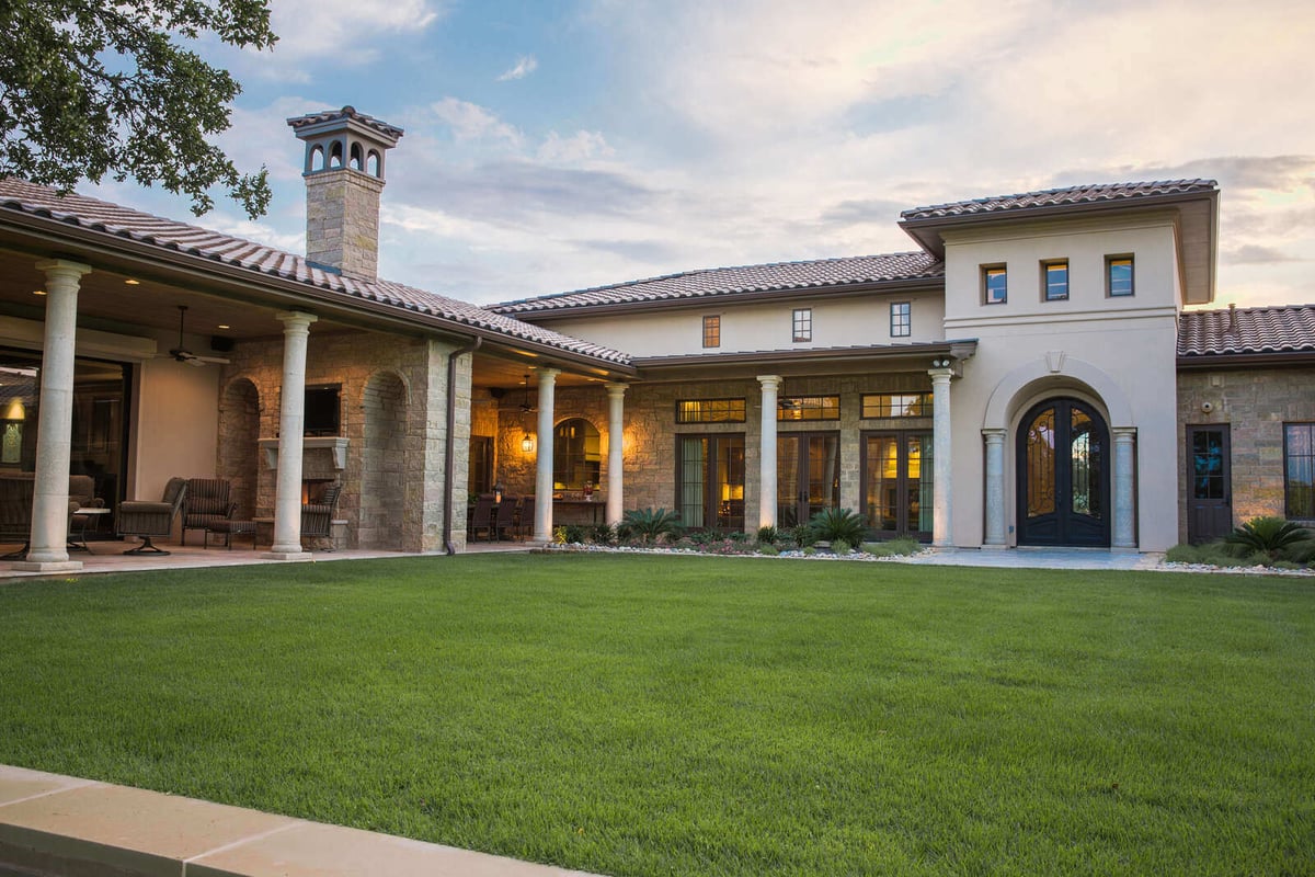 Custom Mediterranean-style home exterior with stone walls and manicured lawn in Georgetown, TX by J Bryant Boyd