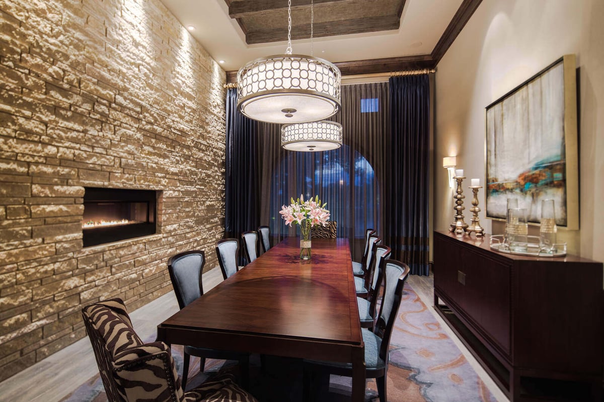 Custom dining room with stone accent wall and modern chandeliers in a Georgetown, TX home by J Bryant Boyd