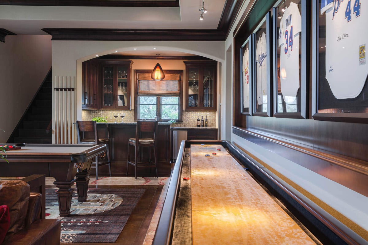 Custom home game room with a shuffleboard table and bar area by J Bryant Boyd in Georgetown, TX