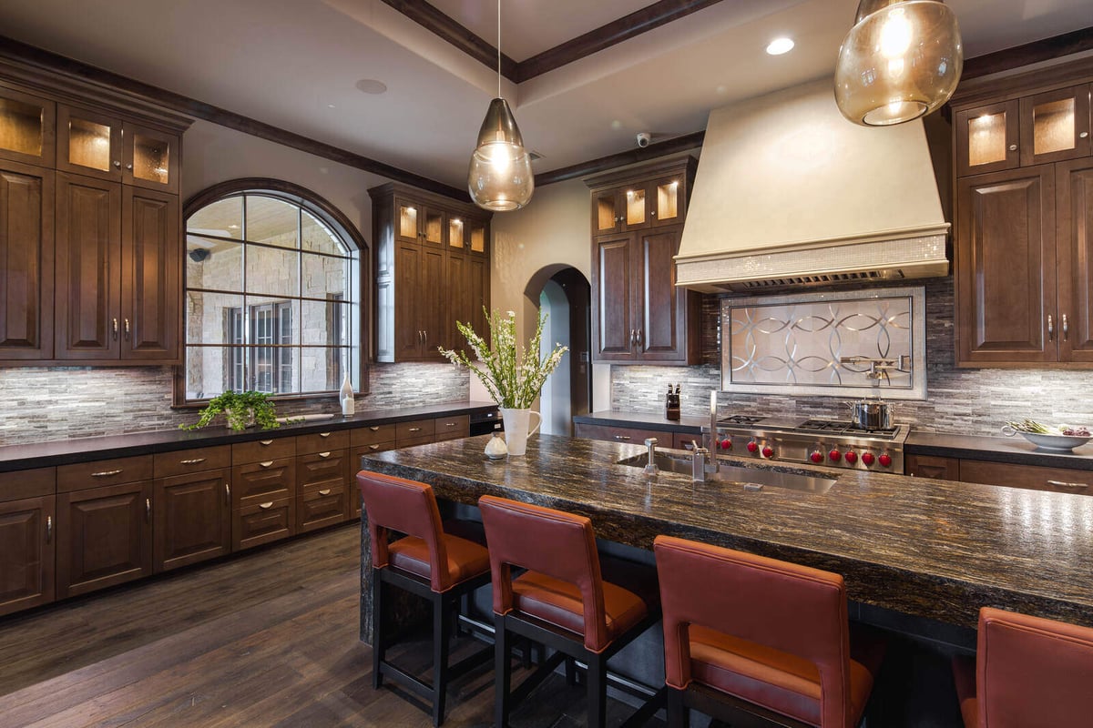 Custom luxury kitchen with dark wood cabinets and large granite island in a J Bryant Boyd home in Georgetown, TX