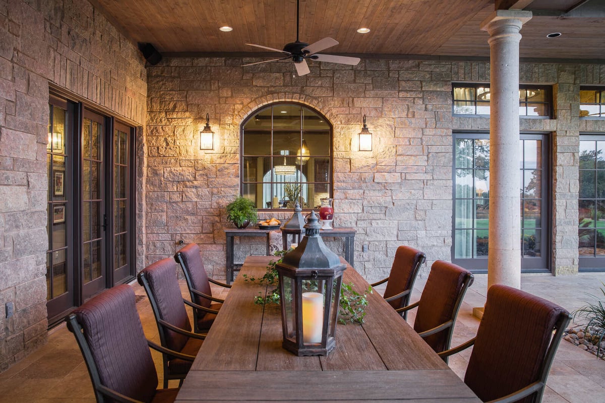 Custom outdoor dining space with stone walls and ceiling fan in a Georgetown, TX home by J Bryant Boyd