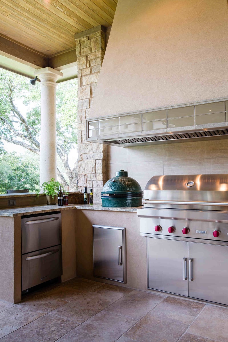 Custom outdoor kitchen with stainless steel appliances and stone columns by J Bryant Boyd in Georgetown, TX