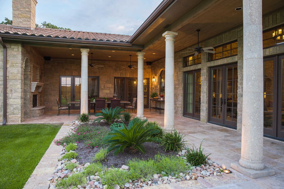 Custom-built backyard patio with stone columns and garden in a Georgetown, TX home by J Bryant Boyd