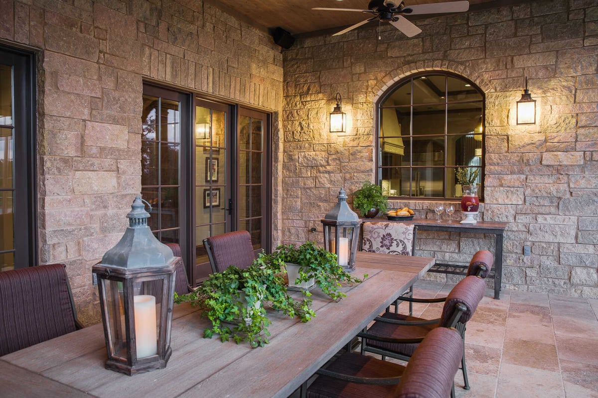 Custom-built outdoor dining area with stone walls and lanterns in a Georgetown, TX home by J Bryant Boyd