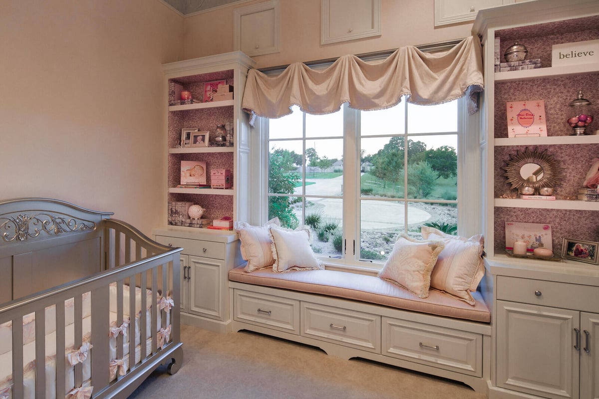 Elegant nursery with a window seat and custom shelving in a J Bryant Boyd home in Georgetown, TX