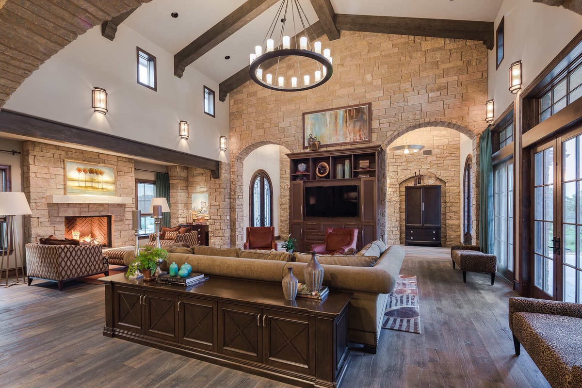 Grand living room with exposed beams and stone fireplace in a custom home by J Bryant Boyd, Georgetown, TX