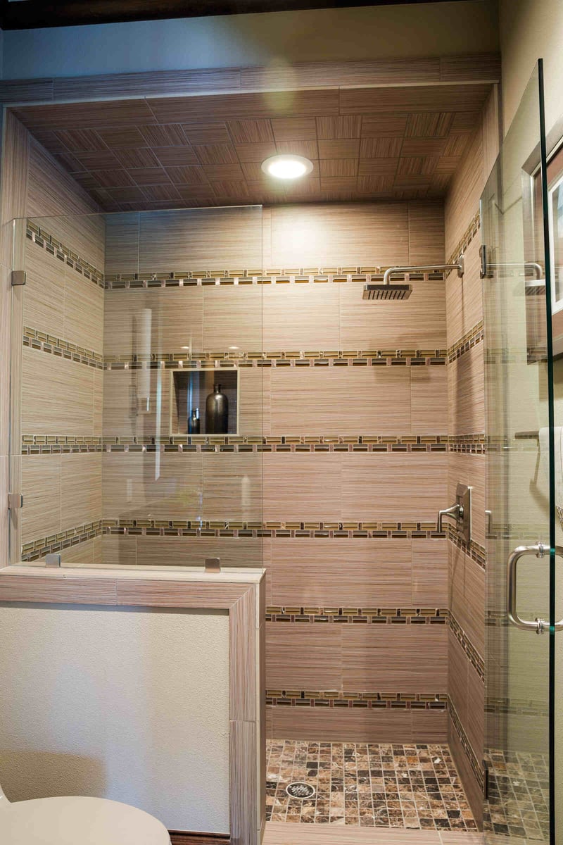 Luxurious custom home shower by J Bryant Boyd in Georgetown, TX, featuring intricate tile work and a modern showerhead