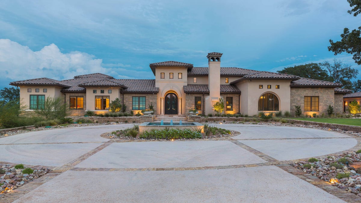 Night view of a custom luxury home with a fountain and stone accents by J Bryant Boyd in Georgetown, TX