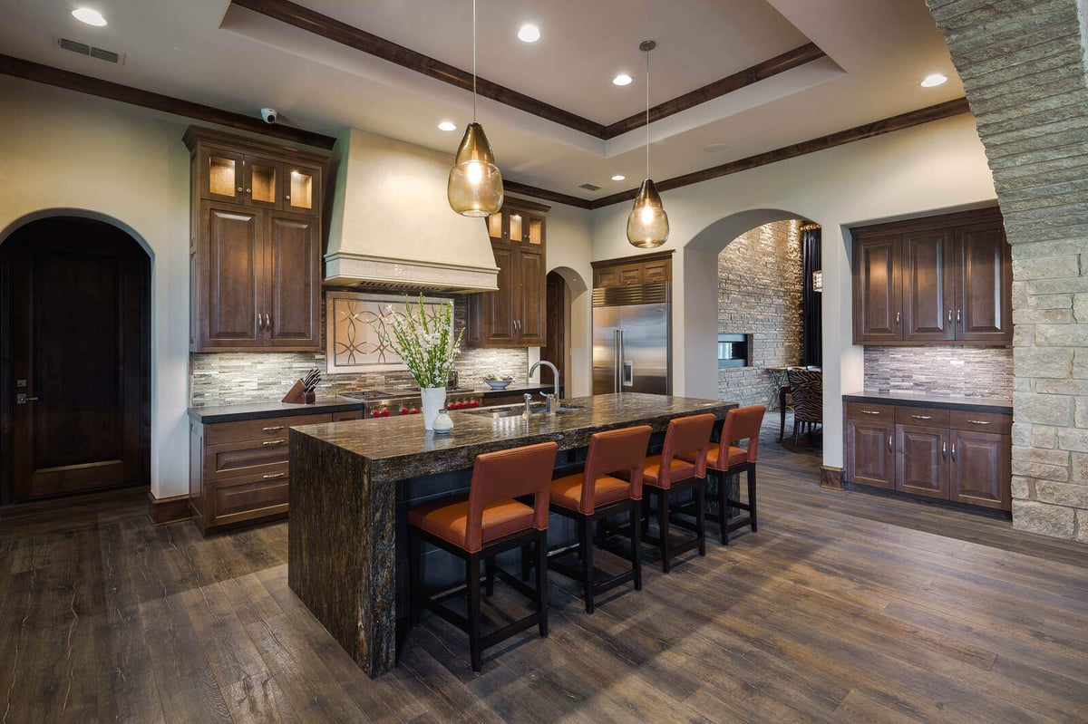 Open-concept kitchen with stone arches and wood finishes in a custom home by J Bryant Boyd in Georgetown, TX