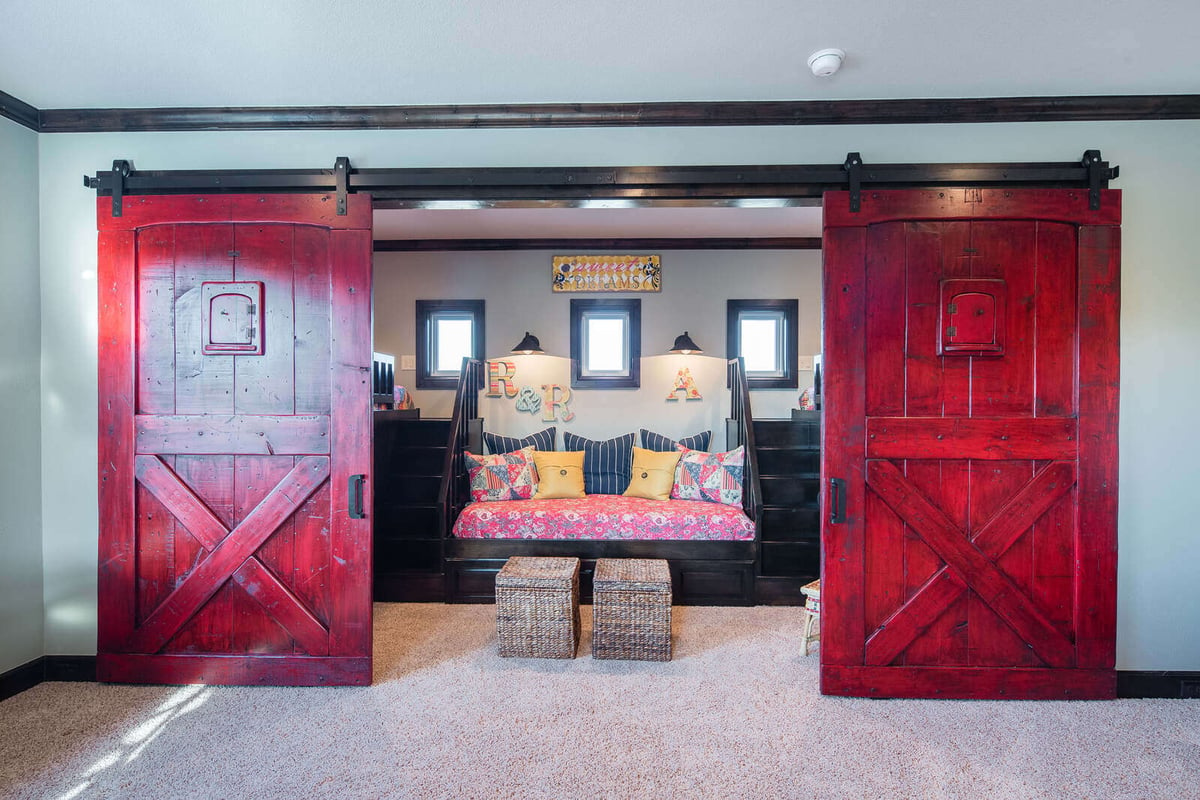 Custom home playroom with red barn doors and built-in seating by J Bryant Boyd in Georgetown, TX