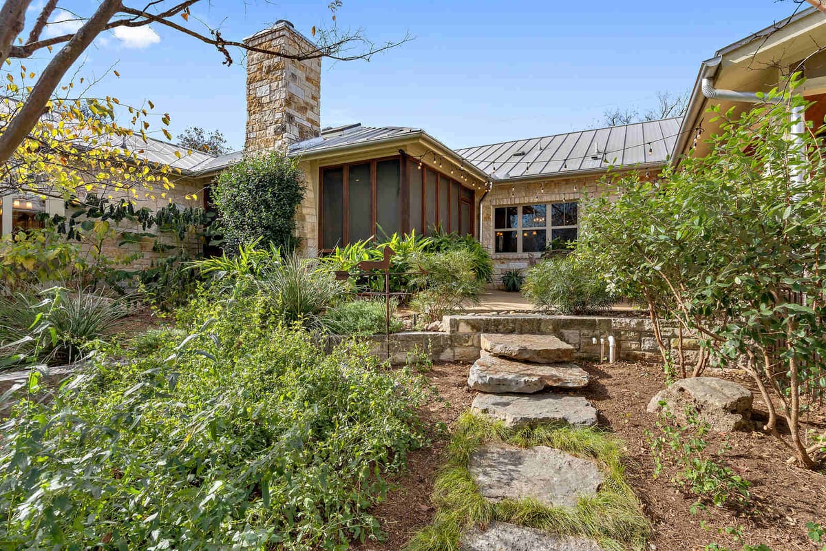 Backyard garden and patio of a custom home with stone exterior by J Bryant Boyd in Georgetown, TX