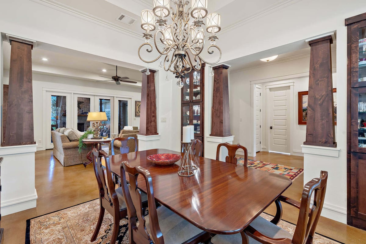 Custom home dining room with elegant chandelier and wooden columns, designed by J Bryant Boyd in Georgetown, TX