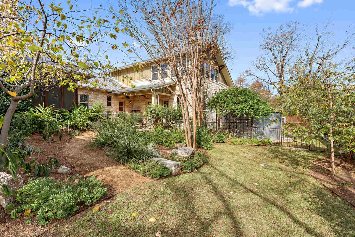 Custom home exterior with stone facade and lush landscaping by J Bryant Boyd in Georgetown, TX