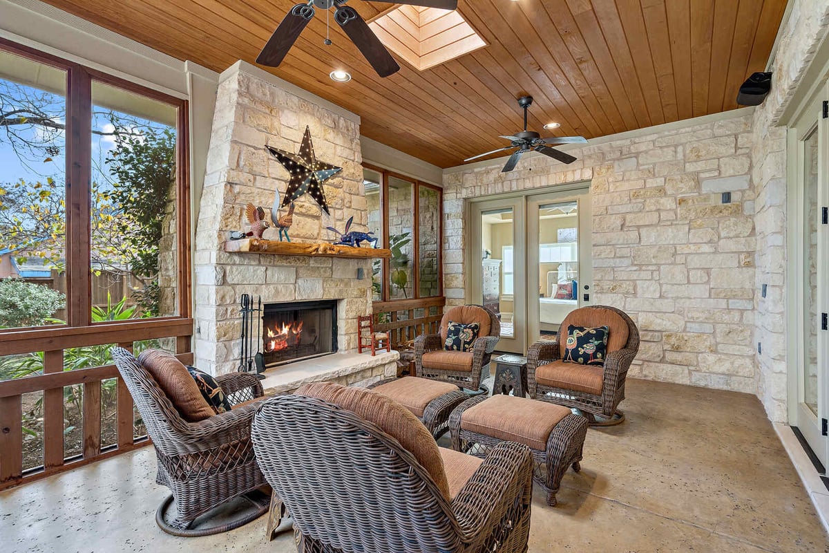 Enclosed patio with a stone fireplace and ceiling fans, custom home by J Bryant Boyd in Georgetown, TX