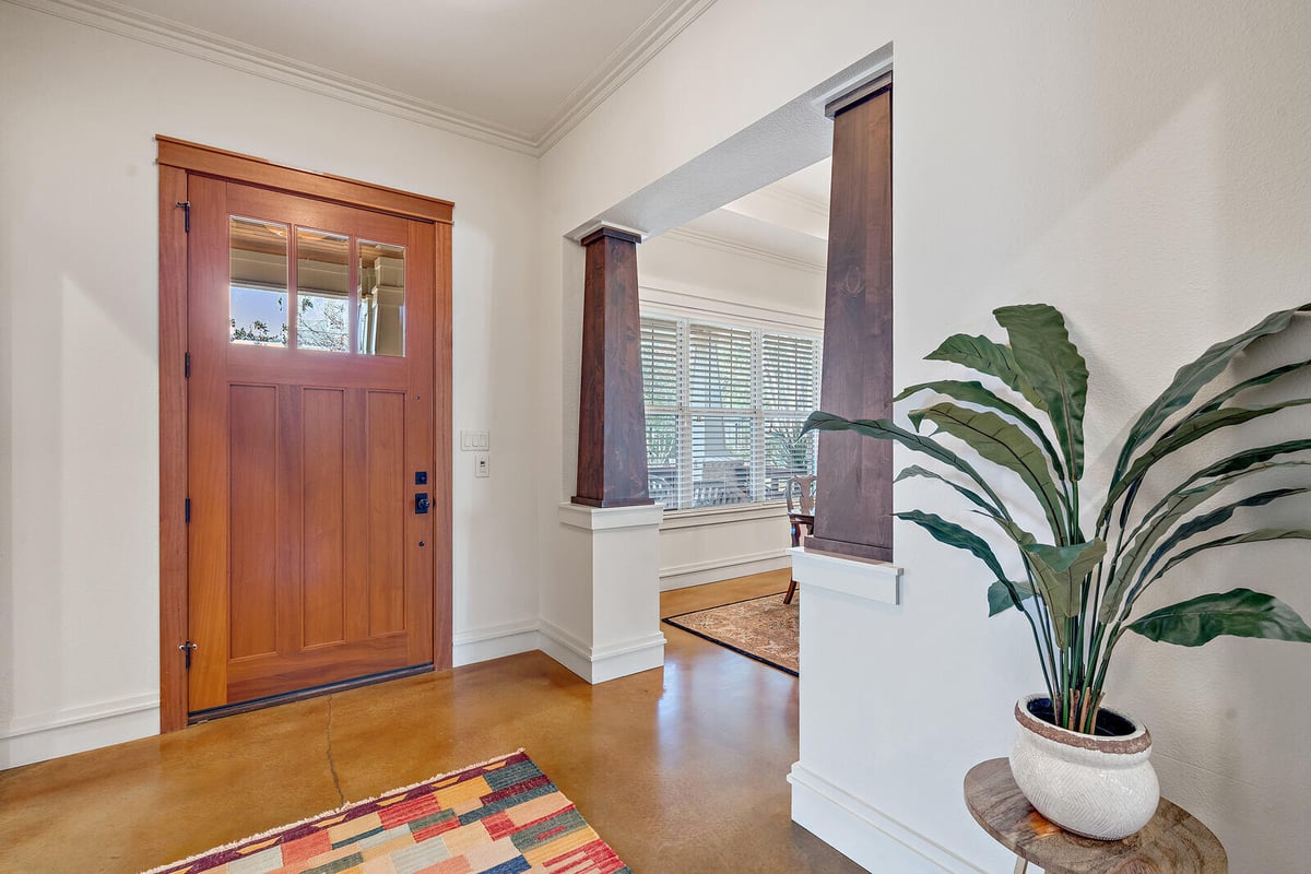 Entrance view of a custom home with wooden door and detailed columns by J Bryant Boyd in Georgetown, TX