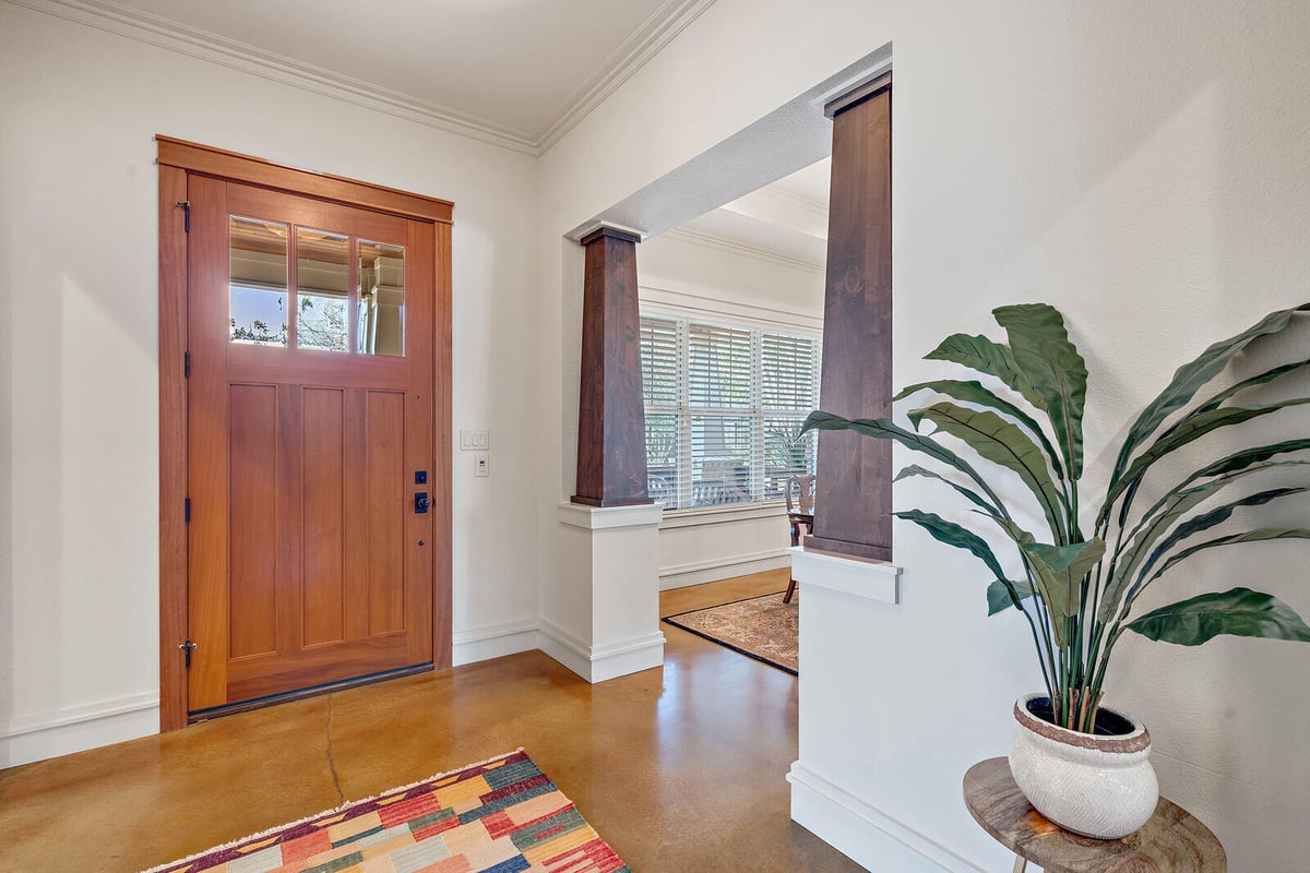 Entrance view of a custom home with wooden door and detailed columns by J Bryant Boyd in Georgetown, TX