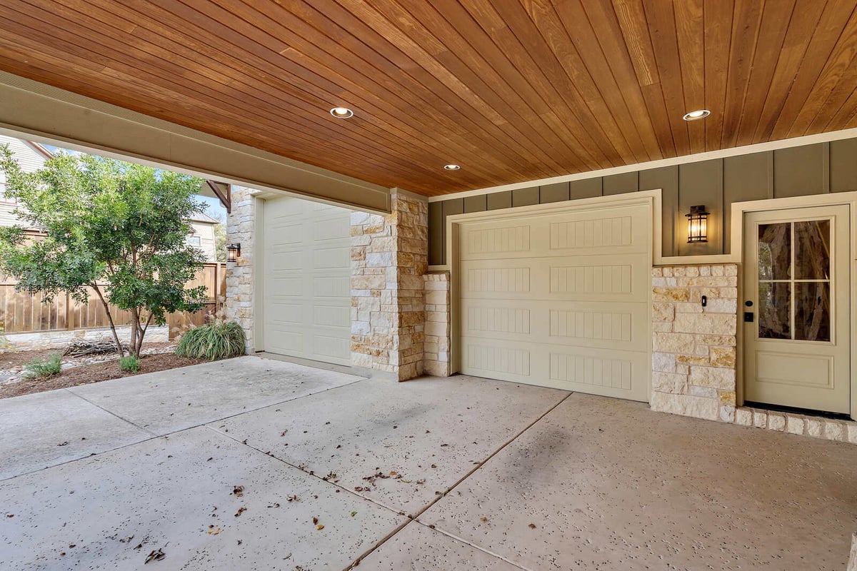 Exterior view of a stone-clad custom home with a metal roof, J Bryant Boyd in Georgetown, TX