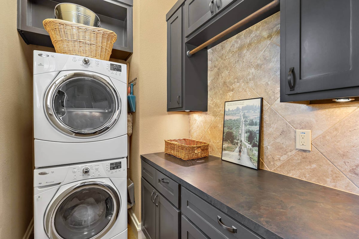 Georgetown, TX custom home featuring a functional laundry room with black cabinetry and a farmhouse sink by J Bryant Boyd