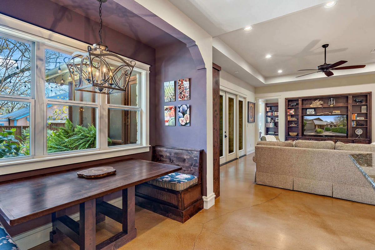 Interior breakfast nook with a rustic wooden table and views of the garden by J Bryant Boyd in Georgetown, TX