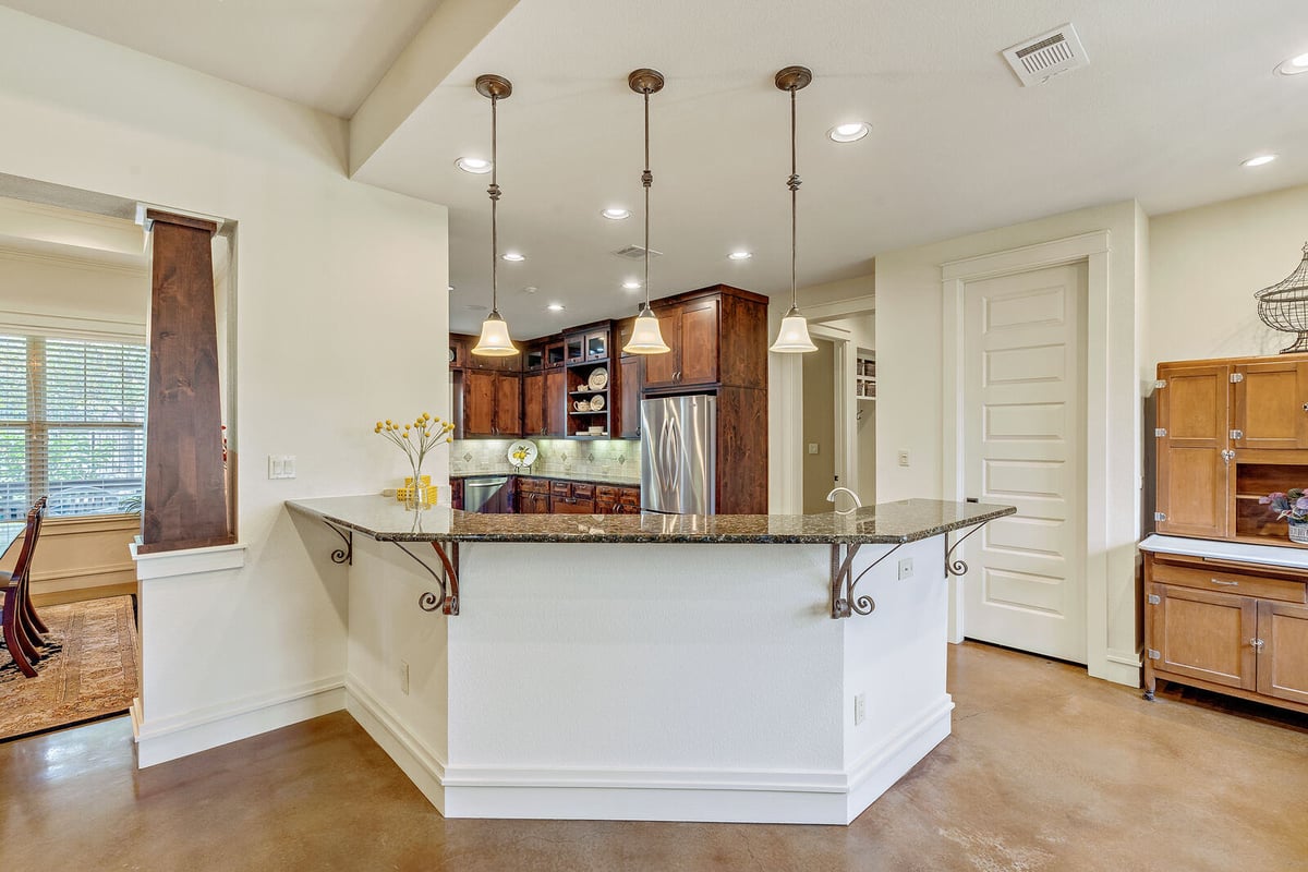 Kitchen island with pendant lighting and granite countertop in a custom home by J Bryant Boyd, Georgetown, TX