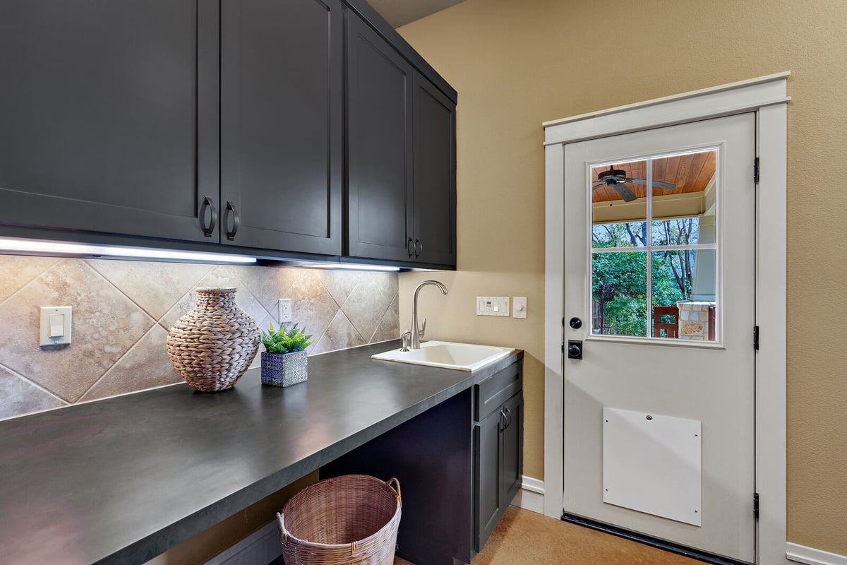 Laundry room with stackable washer and dryer and ample storage in a custom home by J Bryant Boyd, Georgetown, TX