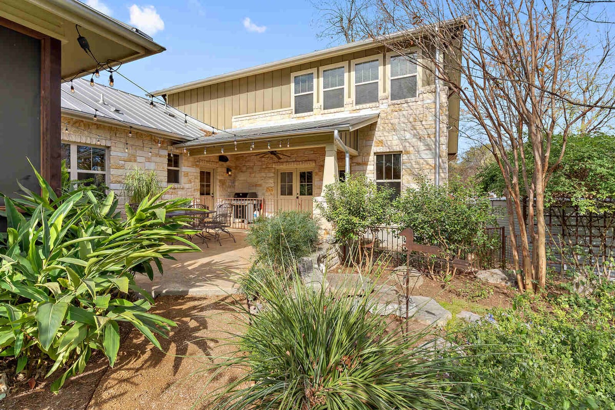 Lush backyard garden with a view of the stone exterior, custom home by J Bryant Boyd in Georgetown, TX