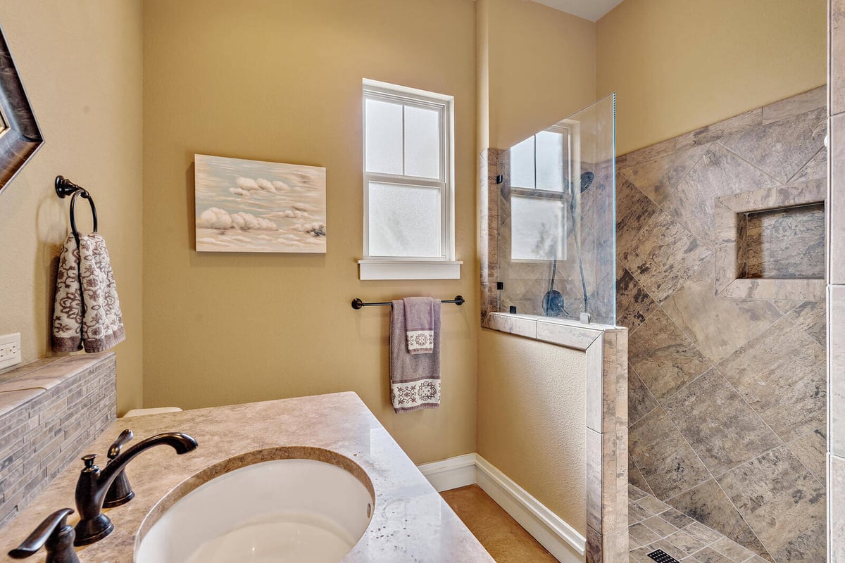 Luxurious bathroom with walk-in shower and granite countertops in a custom home by J Bryant Boyd in Georgetown, TX