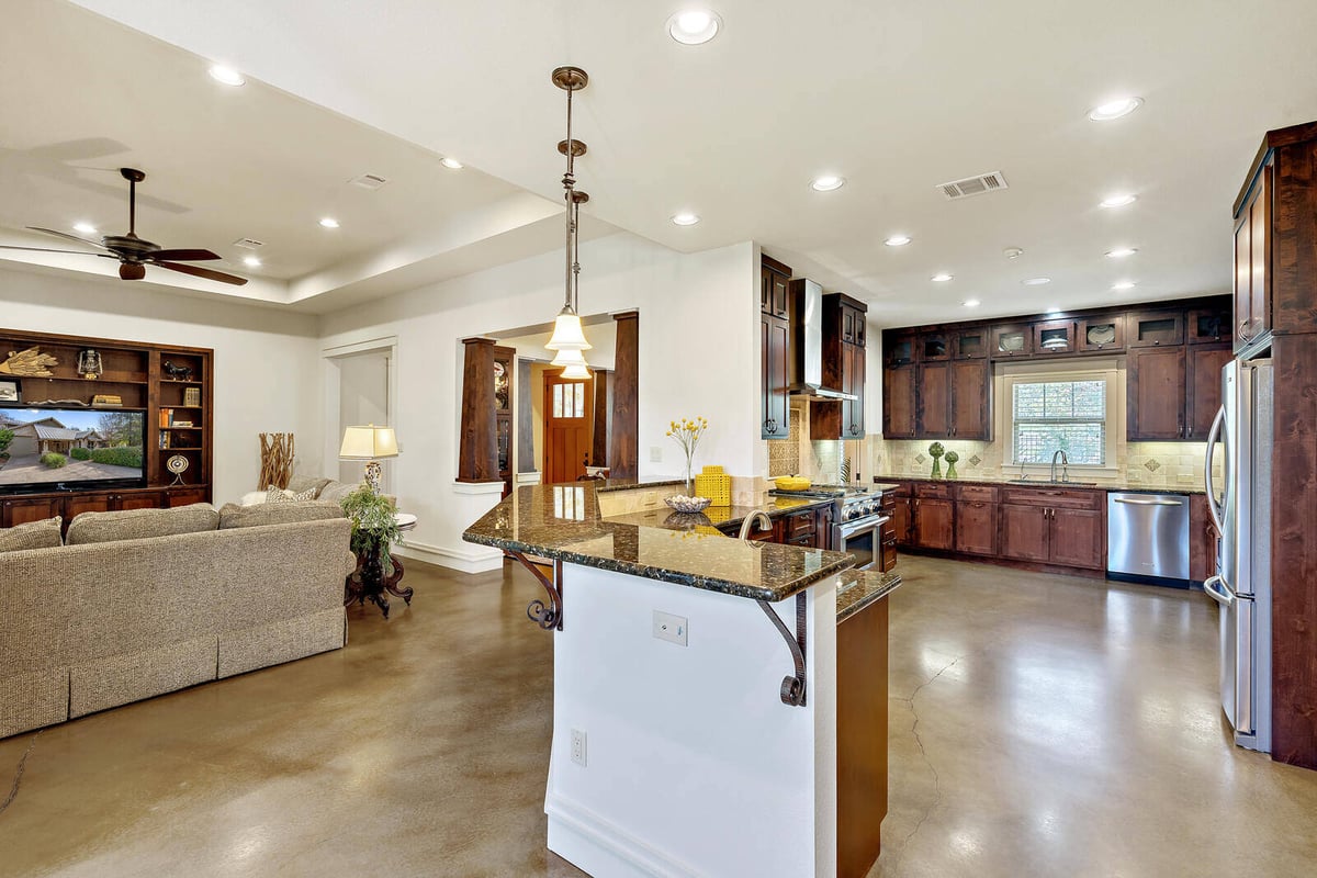 Open-concept living room and kitchen with recessed lighting in a custom home by J Bryant Boyd, Georgetown, TX