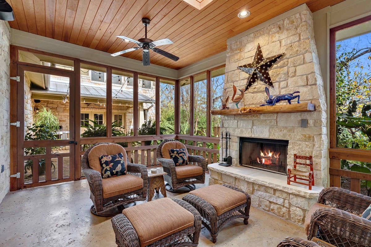 Screened patio with stone fireplace and wicker seating, custom home by J Bryant Boyd in Georgetown, TX