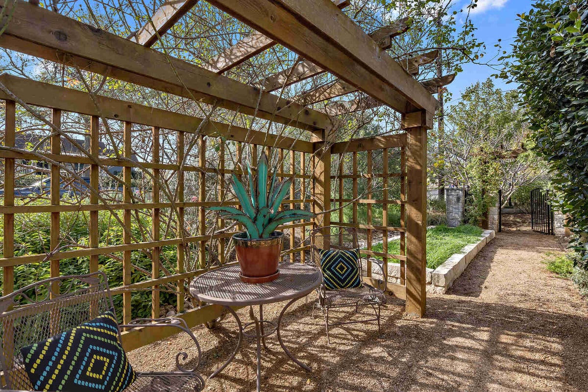 Serene outdoor seating area with trellis and greenery in a custom home by J Bryant Boyd in Georgetown, TX